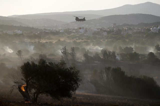 A helicopter battles wildfires south of Athens (Thanassis Stavrakis/AP)
