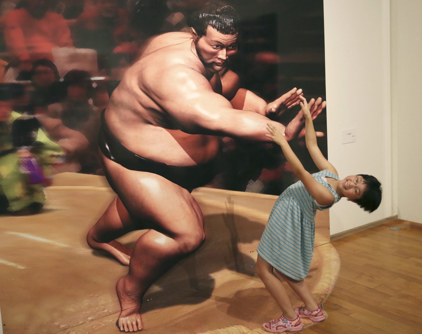 A girl poses with a 3D image at a 3D trick art exhibition by Japanese artist Masashi Hattori in Kawasaki, near Tokyo, Saturday, Aug. 5, 2017. (Koji Sasahara/AP/PA)