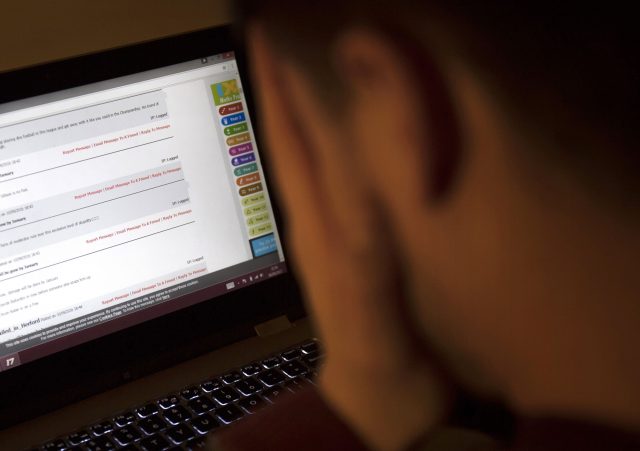 A child looking upset as they look at a laptop computer