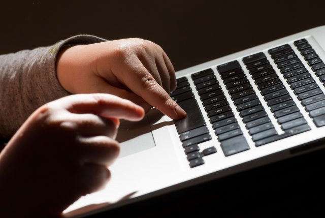 A child's hands on the keys of a laptop keyboard