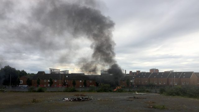 Smoke rises after parked cars set alight by youths burn on Stewart Street in Belfast