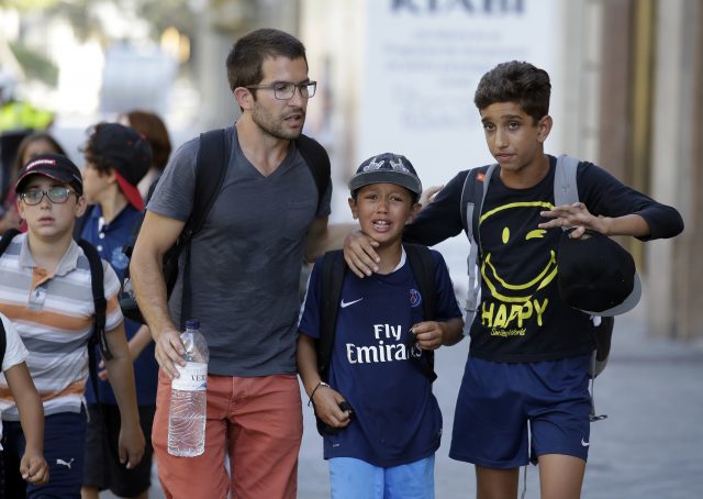 Children, some in tears, are escorted down a road in Barcelona