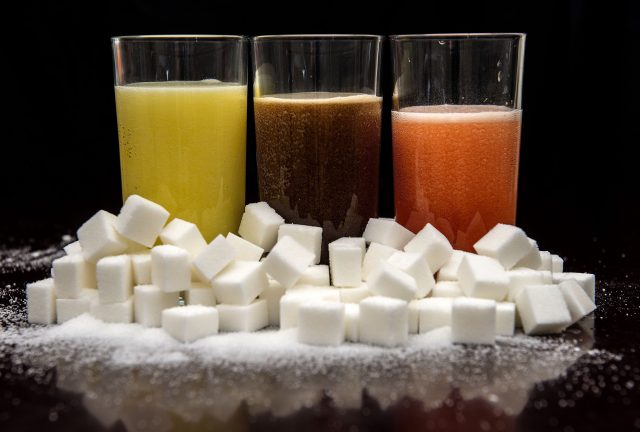 Carbonated drinks surrounded by sugar cubes