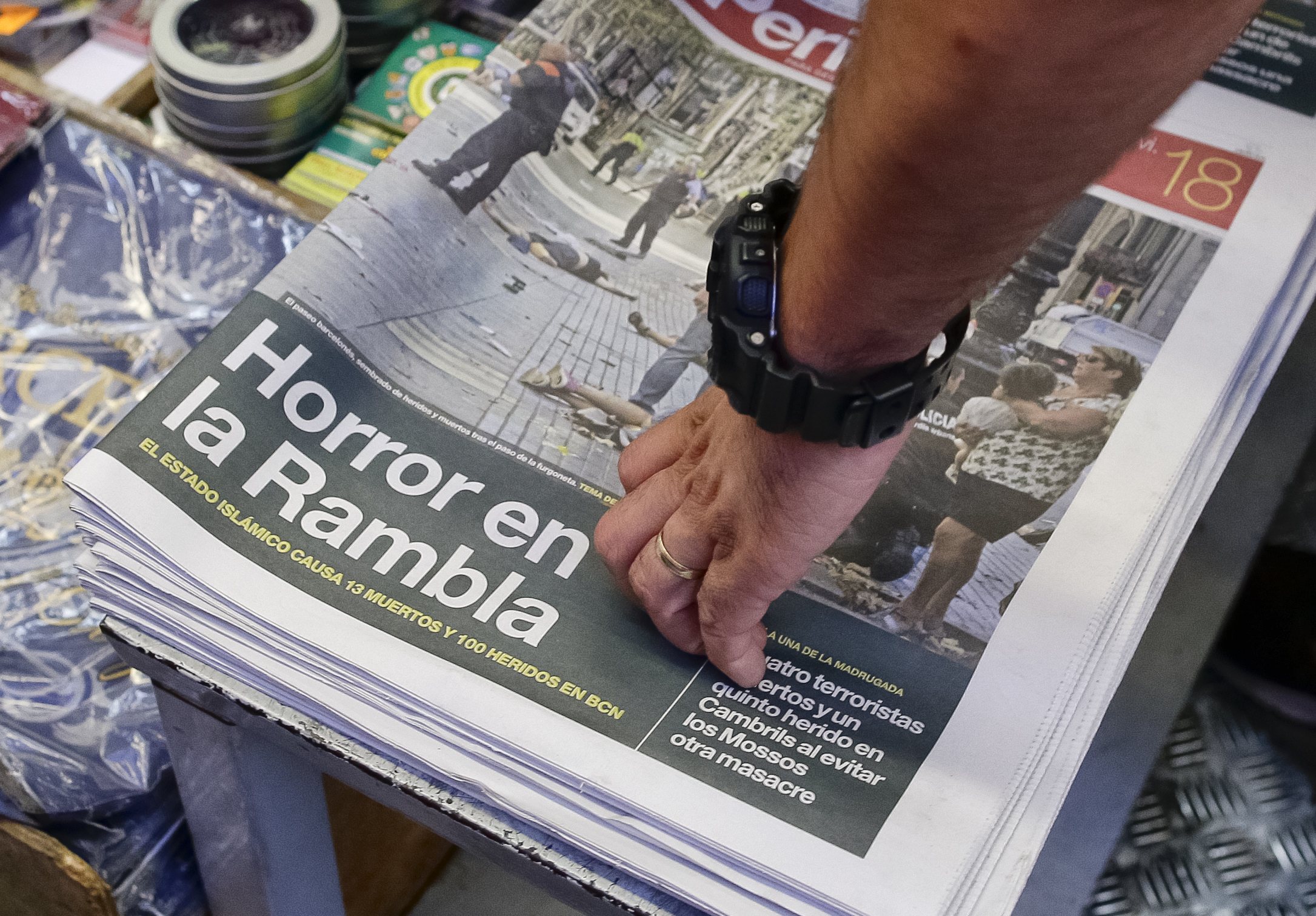 A man touches a newspaper displaying a photograph of the aftermath of the terror attack in Las Ramblas