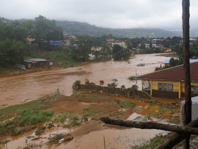 A torrent of water flows through a flooded neighbourhood in Regent, east of Freetown