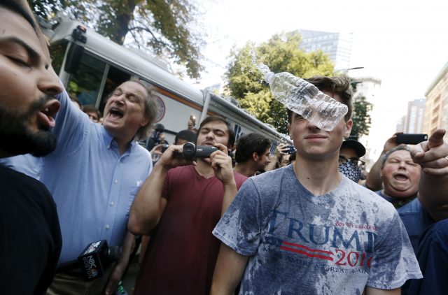 A man wearing a Trump T-shirt is hit by a flying plastic bottle of water (Michael Dwyer/AP)
