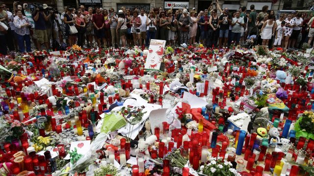 Candles and floral tributes have been placed at the scene where 14 people were killed and 120 were wounded in Barcelona