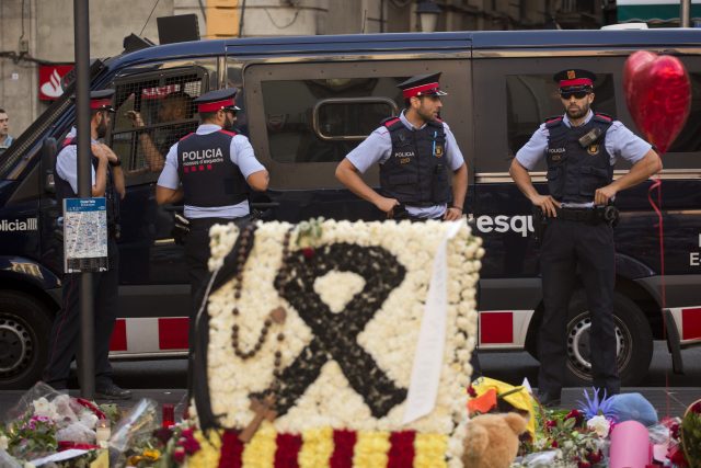 Police stand guard next to flags, flowers, messages and candles on Barcelona's Las Ramblas