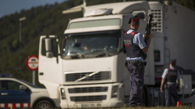 Police officers search a truck as they stand guard in a security checkpoint at the road entrance of Ripoll, north of Barcelona