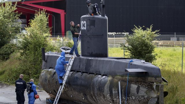 Police technicians board the amateur -built submarine UC3 Nautilus on a pier in Copenhagen harbour