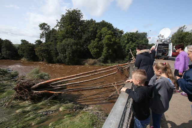 People look at trees in the river Faughan in Drumahoe, Londonderry, after heavy rain left a trail of destruction