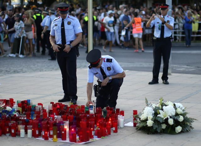 A police officer places a candle during a rally to commemorate those killed in the Barcelona attack
