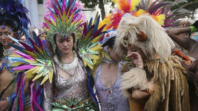 Costumed revellers pause during a moment to honour the victims of the Grenfell Tower fire