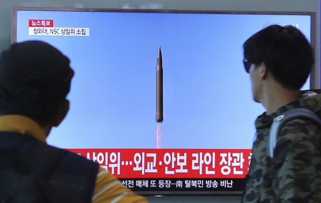 People watch a TV screen showing file footage of a North Korean missile launch (AP)