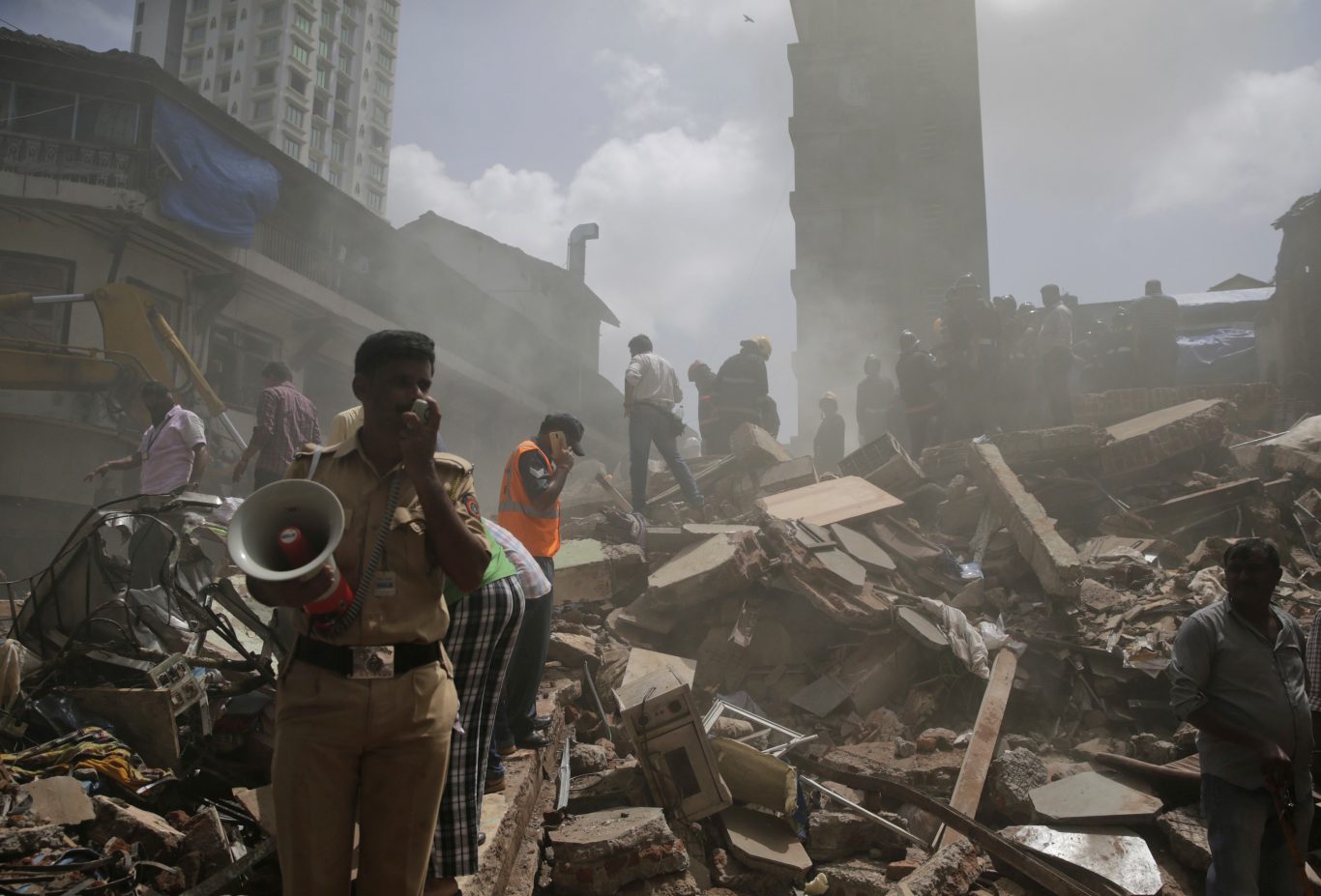A policeman makes an announcement on a loudspeaker at the site of building collapse in Mumbai (Rafiq Maqbool/AP)