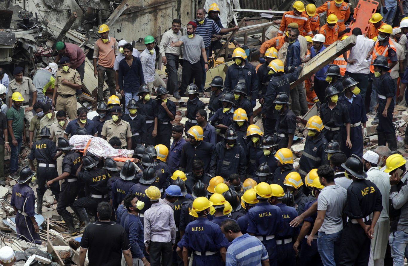 Rescue workers recover the body of a victim (Rafiq Maqbool/AP)