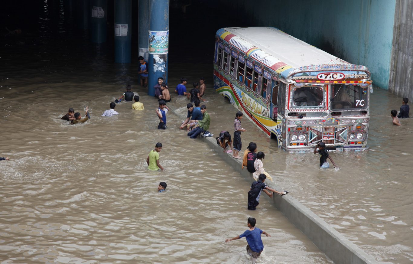 Pakistani children play in an underpass filled with rainwater in Karachi (Fareed Khan/AP)