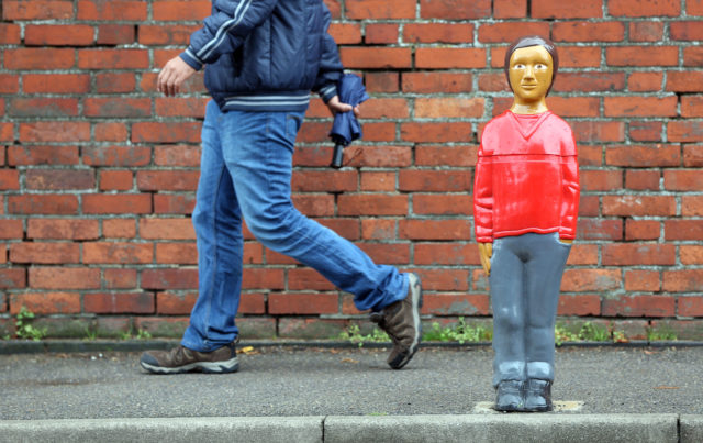 A man walks past a life-sized child shaped bollard