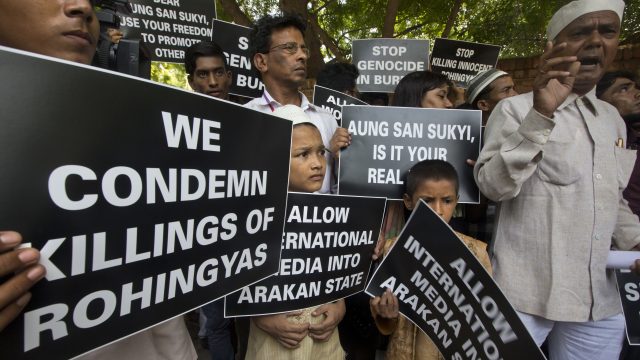 Rohingya men and children hold placards condemning the violence in Myanmar