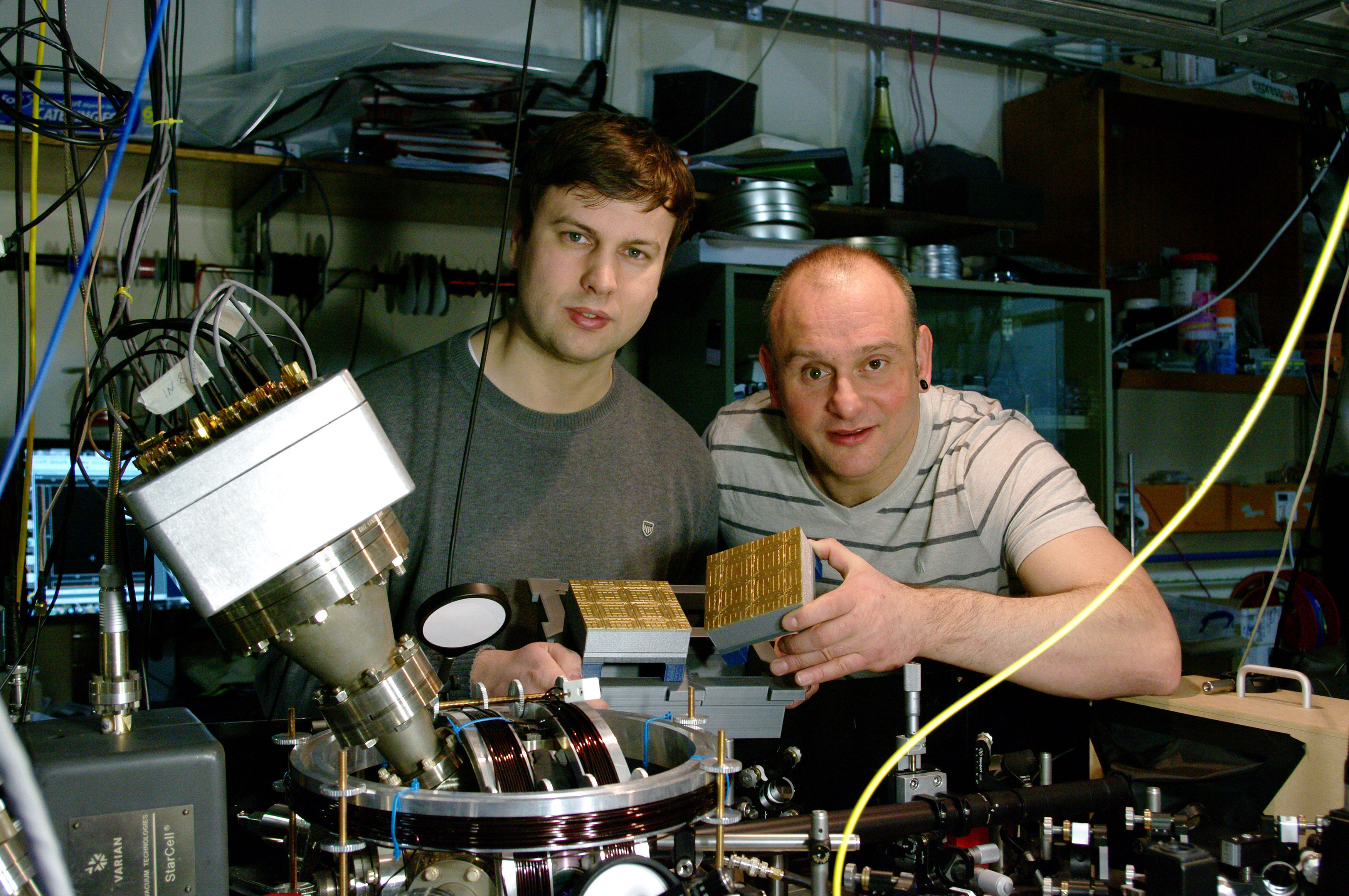 Professor Winfried Hensinger (right) and Dr Bjoern Lekitsch (left) with a quantum computer blueprint model behind a quantum computer prototype at the University of Sussex earlier in 2017