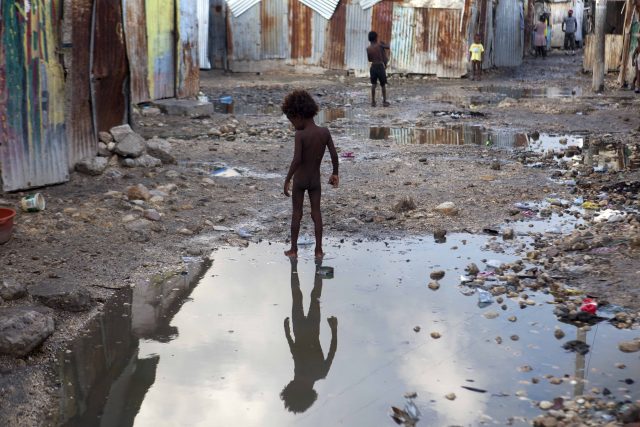 A child plays in a puddle in the seaside slum of Port-au-Prince, Haiti