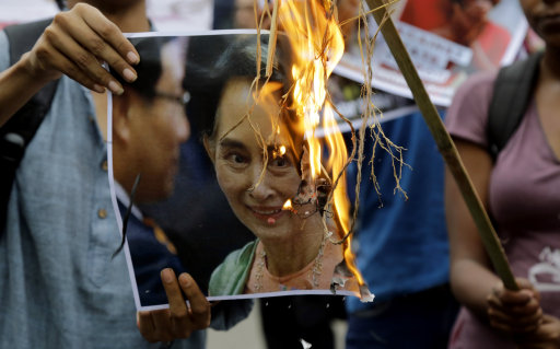 Protestor in India holds a burning image of Aung San Suu Kyi (Bikas Das/AP)