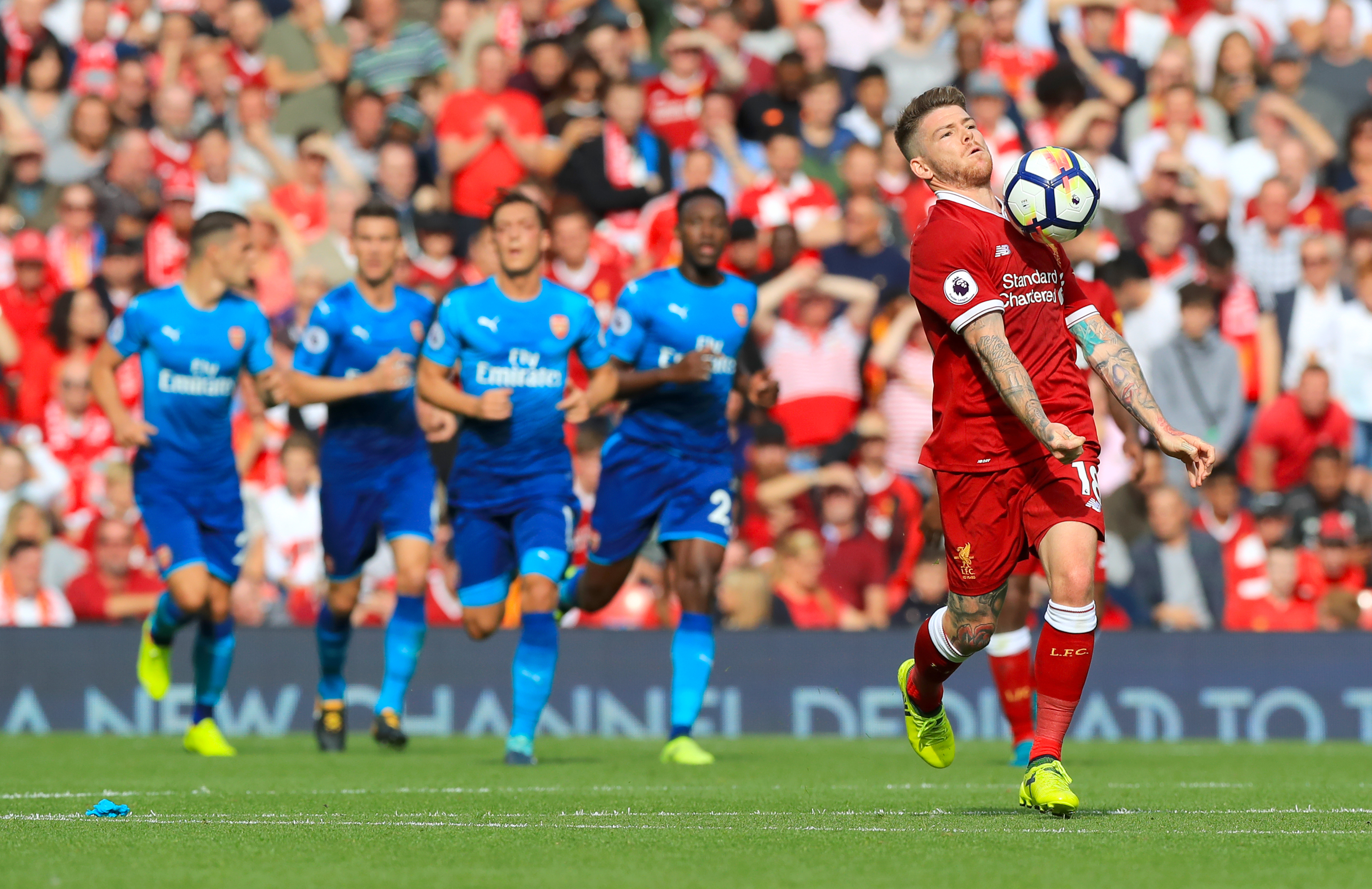 Arsenal players watch on as Alberto Moreno runs with the ball