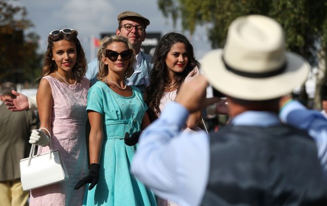 A man poses for a photograph with Goodwood Revival models (Andrew Matthews/PA)