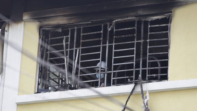 Forensic police officer investigates burnt windows at an Islamic religious school following a fire on the outskirts of Kuala Lumpur