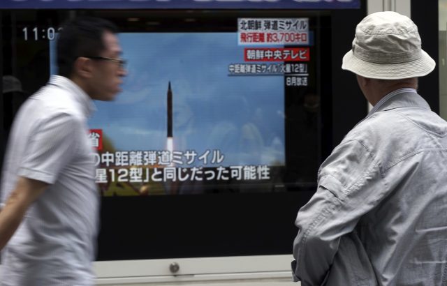 A man, right, watches a public TV screen broadcasting news of North Korea's missile launch