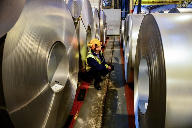 A worker inspecting rolls of steel