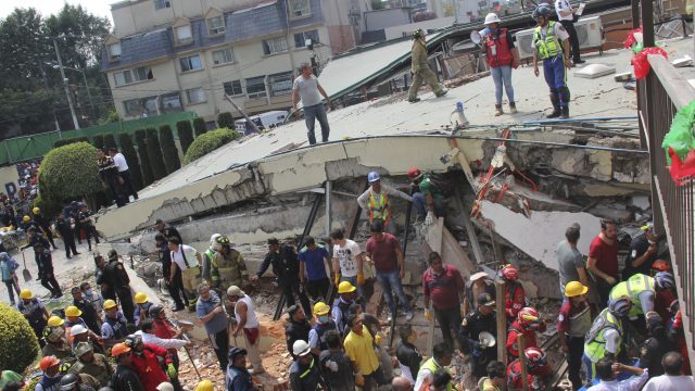 Rescue workers search for children trapped inside the collapsed Enrique Rebsamen school in Mexico City (Carlos Cisneros/AP)