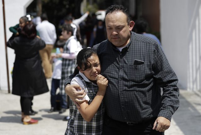 A man comforts a frightened student as he collects her from her school in the Roma neighborhood of Mexico City (Rebecca Blackwell/AP)