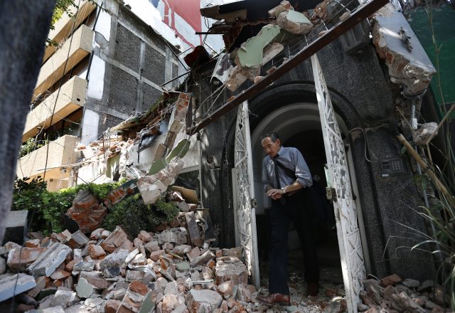 A man walks through a door frame of a building that collapsed in Mexico City 