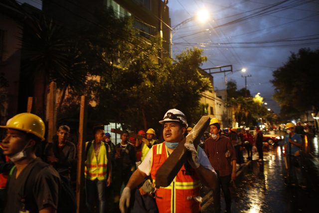 Men carrying beams of wood offer their services at a site of earthquake damage in in Mexico City