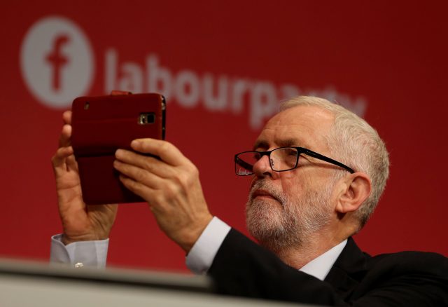 Jeremy Corbyn takes a photograph as he listens to speeches