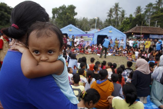 A woman carries her baby at an evacuation camp