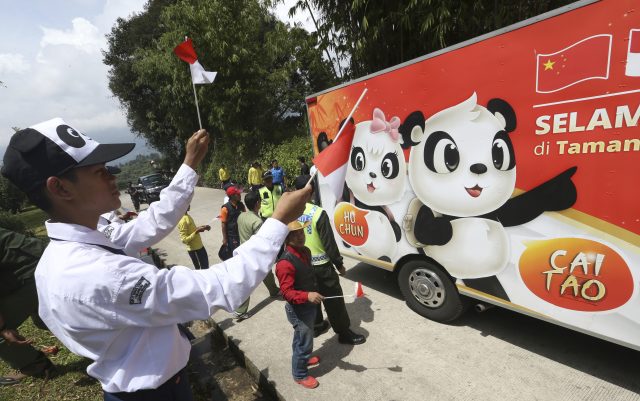 Indonesian students cheer a truck carrying a male giant panda from China
