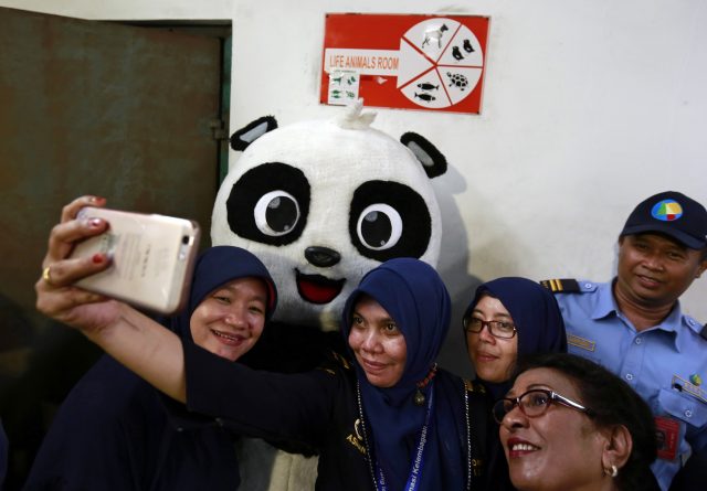 Indonesian Customs officers take a selfie with a worker in panda costume during the arrival ceremony