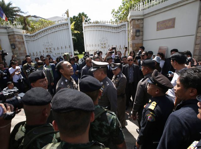 Thai policemen and soldiers gather in front of the house of former Prime Minister Yingluck Shinawatra with a search warrant