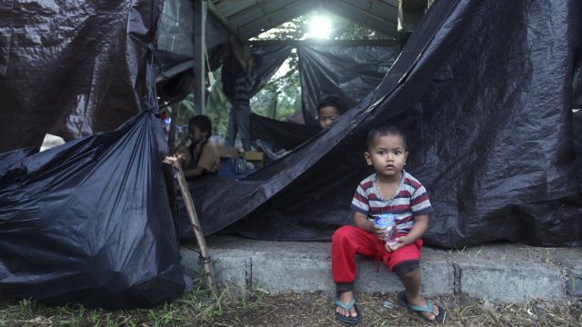 A boy sits in front of his shelter at an evacuee camp outside the Mount Agung volcano in Karangasem, Bali