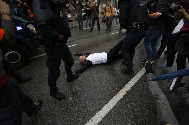 Spanish National Police drags away a man lying on the street