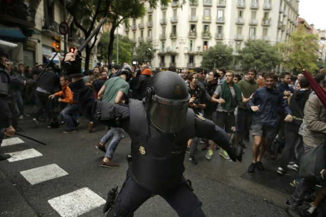 Spanish riot police swings a club against would-be voters