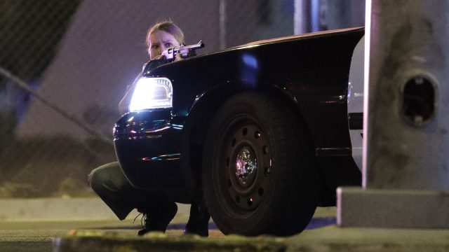 A police officer takes cover behind a police vehicle during a shooting near the Mandalay Bay resort and casino on the Las Vegas Strip (John Locher/AP)