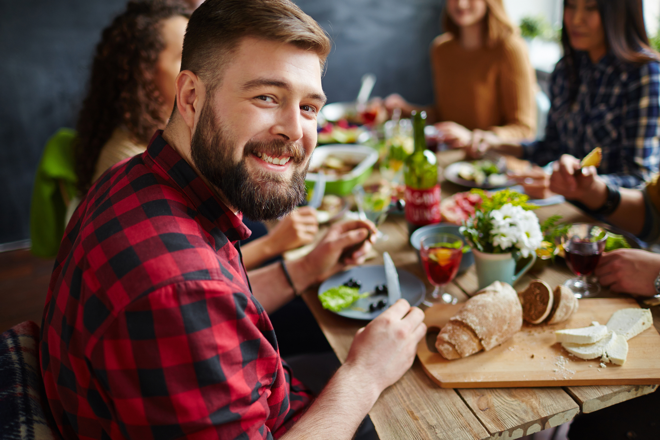 Young man sitting at dinner table with his friends and smiling at camera (Thinkstock/PA)