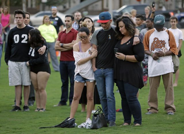 People embrace and bow their heads as nearby church bells ring during a vigil in Orlando, Florida (John Raoux/AP)