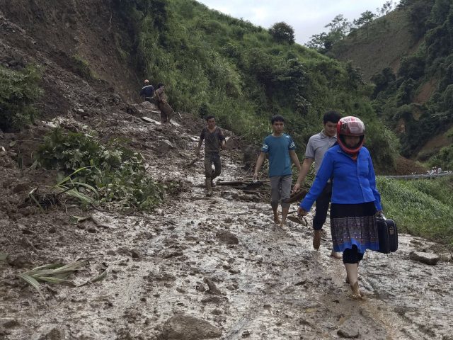 Residents walk along a muddy road which was damaged by a landslide in Vietnam