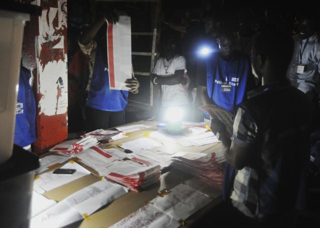 Electoral officials use a lantern as they count ballot papers at the end of voting at a polling station in Monrovia