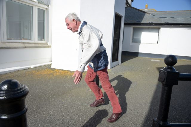 A man struggles to walk in strong winds at Lands End, Cornwall 