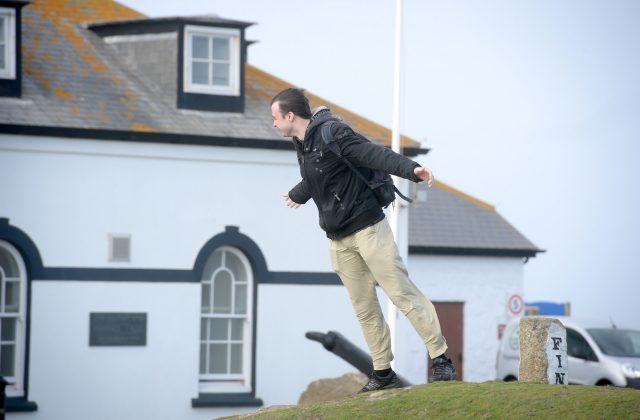 A man struggles to stand up in strong winds in Cornwall 